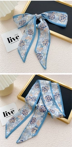 Vue détaillée d'un foulard étroit bleu ciel à fleurs noué en élégant nœud