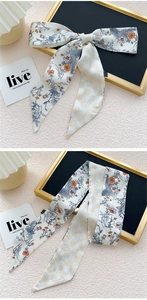 Détail d'un bandeau en soie à motifs floraux et damiers noué en boucle et plié