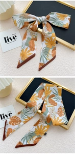 Détail d'un foulard twilly à imprimé feuilles tropicales noué en nœud sur un plateau