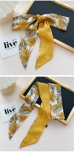 Détail du bandeau en soie jaune avec motif de feuilles tropicales noué en nœud