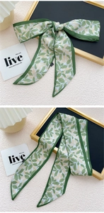 Détail d'un ruban à cheveux en soie à motif de feuilles vertes noué en joli nœud
