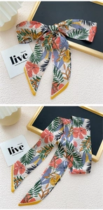 Détail d'un foulard étroit à motif tropical noué en boucle et en ruban plat
