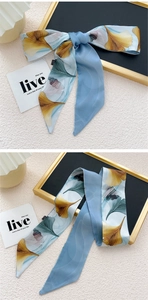 Détail d'un foulard en soie bleue avec motifs de feuilles de ginkgo dorées en nœud