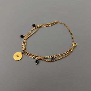 Dettaglio del bracciale dorato multistrato con perline malocchio e ciondolo inciso