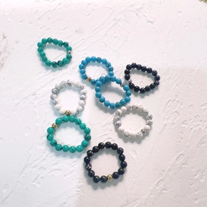 Set of 8 elastic beaded rings with natural stones and metal beads on white stone
