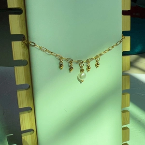 Détail d'un collier plaqué or 18K avec de petites billes et un pendentif en perle d'eau douce