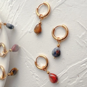 Detailed view of drop-shaped tiger eye and agate stones on 18k gold-plated hoop earrings