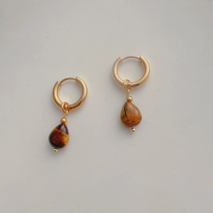 Detailed view of 18k gold drop earrings with teardrop tiger eye stone pendants