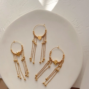 18K gold plated tassel earrings with heart and star charms on a ceramic plate