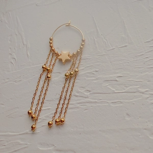 Detail of 18K gold star charm and long chain tassels on a stainless steel hoop earring