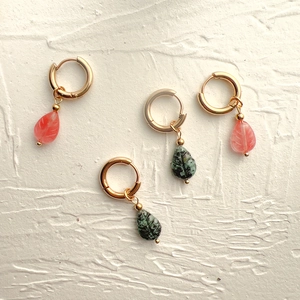 Détail de boucles d'oreilles créoles en acier doré 18K avec pendentifs feuille en pierre
