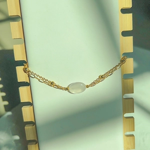 Detail of double-layer gold chain bracelet with oval translucent natural stone on display