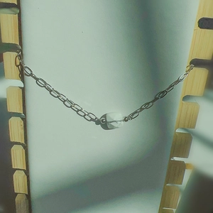 Détail du bracelet chaîne argentée avec une pierre carrée en marbre blanc veiné