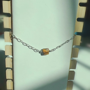 Détail du bracelet en chaîne argentée avec œil de tigre carré sur support d'exposition