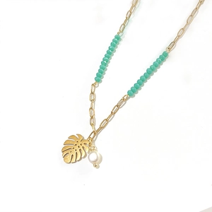 Detailed view of monstera leaf pendant with green beads and pearl on a gold chain necklace