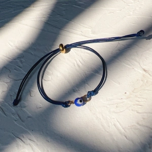 Detailed view of dark blue braided evil eye bracelet with adjustable golden slider bead