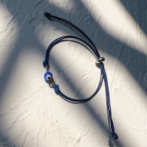 Macro detail of blue adjustable woven evil eye bracelet with central glass bead decoration