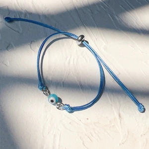 Detail of blue braided evil eye bracelet with adjustable silver sliding closure on stone