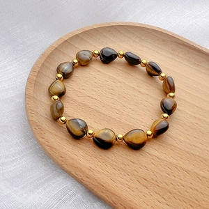 Vintage tiger eye stone beaded bracelet with gold accents on a rustic wooden display