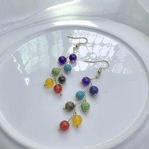 Détail de boucles d'oreilles chakra colorées avec pierres et crochets dorés