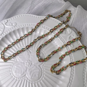 Detail of colorful enamel chain necklace with lobster clasp on elegant white floral plate