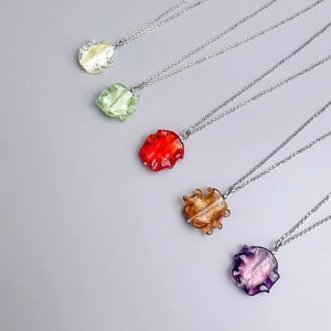 Macro detail of bohemian glass pendants with gold leaf inserts on thin metal necklaces