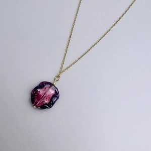 Detail view of purple gradient floral glass pendant on a gold stainless steel chain