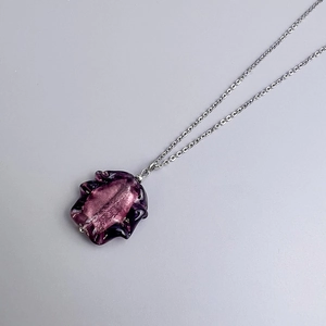 Macro shot of irregular purple glass pendant with textured silver stainless steel chain