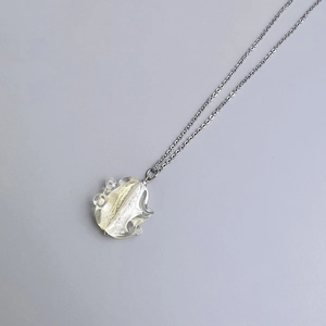 Macro detail of bohemian stainless steel necklace featuring a crinkled glass pendant