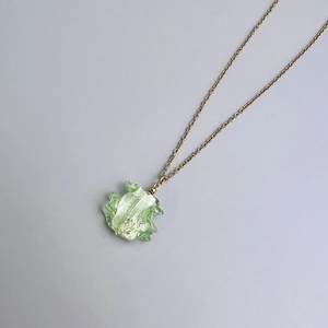 Detailed macro of a green wavy resin pendant necklace with gold leaf foil on gold chain