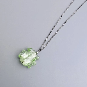 Detail of light green irregularly shaped glass pendant on a silver stainless steel chain