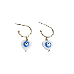 Golden C-shaped hoop earrings featuring white heart charms with blue evil eye motifs