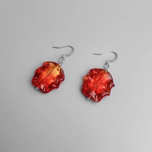 Détail de boucles d'oreilles pendantes en verre froissé rouge-orange avec flocons d'or
