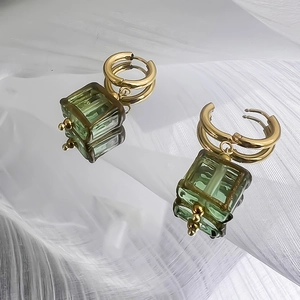 Vue macro détaillée de boucles d'oreilles en acier doré 18 carats avec pendentifs verts