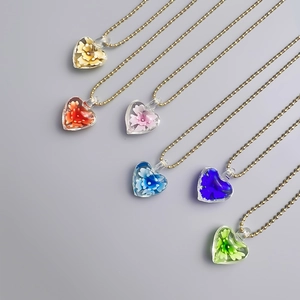 Nahaufnahme leuchtender Herz-Glasblumen-Halsketten in sechs Farben mit goldenen Kugelkette