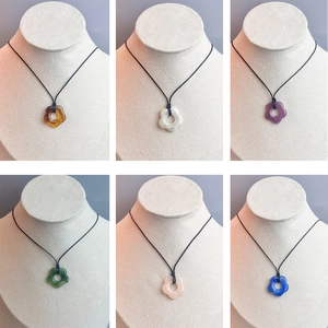 Collection of six vibrant bohemian hollow floral resin pendant necklaces on white displays