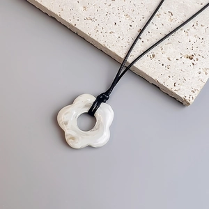 Detail of bohemian wax cord necklace featuring a white marble texture flower pendant