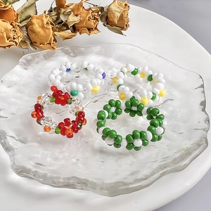 Handmade woven flower bead rings set featuring colorful floral patterns on glass tray