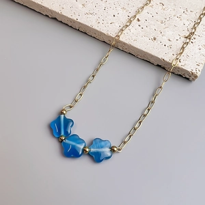 Détail du collier en acier doré 18K avec pendentifs fleurs en pierre œil-de-chat bleue