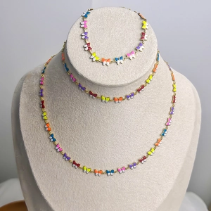Vergoldetes Schmuckset aus Edelstahl mit bunten Emaille-Schmetterlingen auf einem Ständer