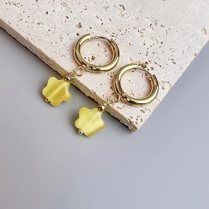 Vue détaillée des boucles d'oreilles fleur en opale dorée sur une pierre de travertin