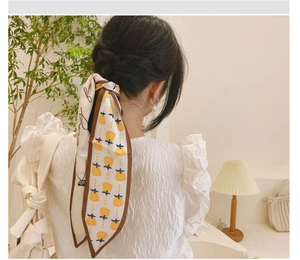 Détail d'un ruban à cheveux en soie à fleurs noué sur une tresse longue pour femme
