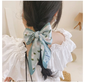 Gros plan d'un ruban à cheveux en soie à fleurs vert clair noué en nœud élégant