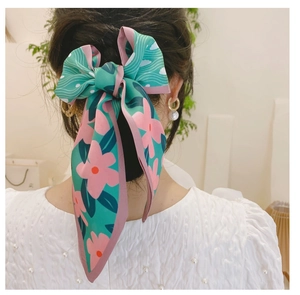 Détail d'un foulard en soie floral noué en grand nœud sur une queue de cheval