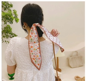 Ruban à cheveux long à fleurs noué sur une tresse dans une ambiance intérieure douce