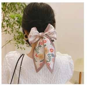Détail d'un nœud papillon en satin à fleurs avec rubans sur une coiffure en queue de cheval
