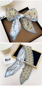 Détail d'une écharpe en soie à motif floral avec texte hello spring et bordure grise