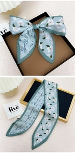Détail d'un foulard en soie fleurie vert clair noué en ruban avec texture satinée