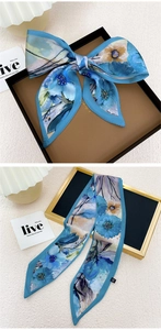Détail d'un foulard en soie bleu à fleurs noué en boucle sur un support élégant