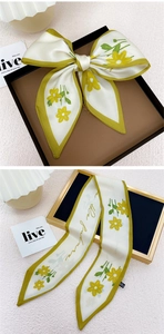 Détail d'un foulard en soie crème avec motifs de marguerites jaunes et bordure verte